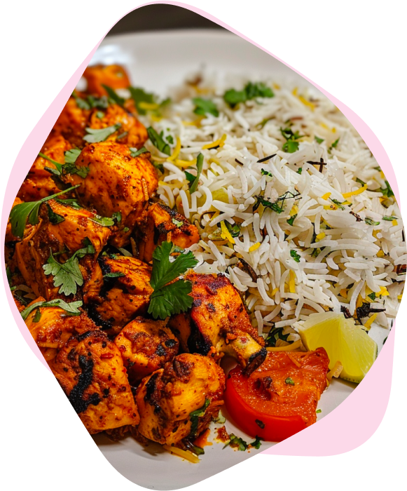 Spiced chicken pieces with rice, coriander and a lime wedge